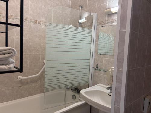 a bathroom with a sink and a tub and a toilet at Cit'Hôtel Beausoleil DAX in Dax