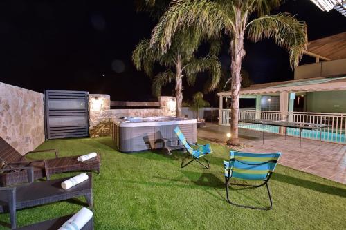 a yard with chairs and a pool at night at וילה גליתא - בריכה , ג'קוזי ונוף in ‘Ein Ya‘aqov