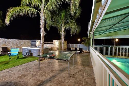 a patio with a table and a swimming pool at night at וילה גליתא - בריכה , ג'קוזי ונוף in ‘Ein Ya‘aqov