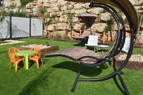 a swing set in a yard with chairs and a table at וילה גליתא - בריכה , ג'קוזי ונוף in ‘Ein Ya‘aqov