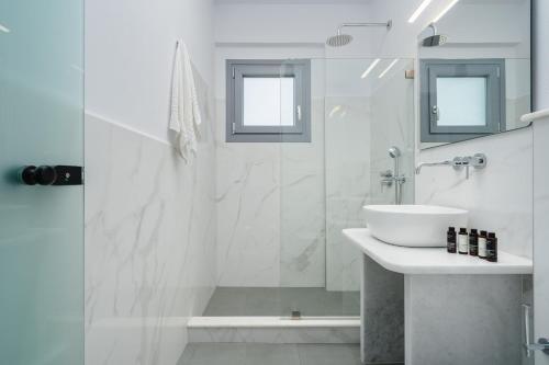 a white bathroom with a shower and a sink at Terracotta Sunset Naxos in Galanádhon