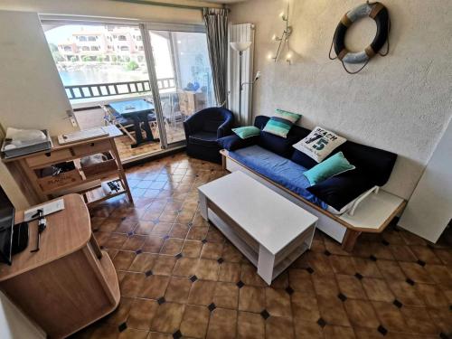 un salon avec un canapé bleu et une table dans l'établissement Résidence Les Maisons De La Crique - APPT DEUX PIECES 4 couchages - LE BARCARES. Réf: 7MCR_15B3 MAE-0283, au Barcarès
