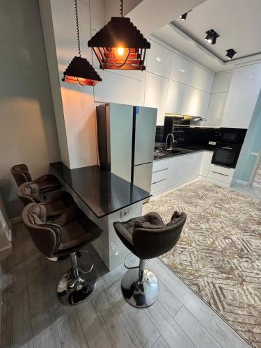 a kitchen with a black counter and some chairs at Vista Dushanbe urban Comfort 3 Bedrooms and Lounge Space in Dushanbe