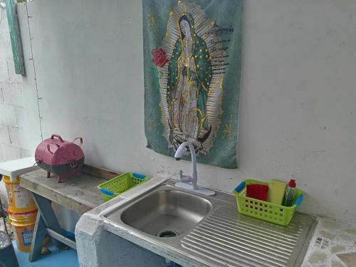 eine Küchenspüle mit einem Vogelbild an der Wand in der Unterkunft Habitación sencilla en la Casa del Colibrí in Celestún