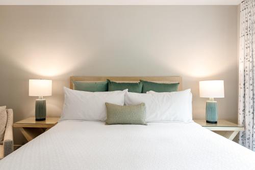a bedroom with a large white bed with two lamps at Avila Village Inn in Avila Beach