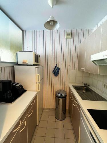 une petite cuisine avec un évier et un réfrigérateur dans l'établissement Résidence Heliodore - Arcachon - Charmant T2 en bord de plage MAE-9114, à Arcachon