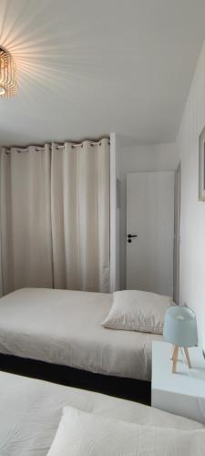 a white bedroom with a bed and a chandelier at Ti vakansin war aod an emrodez in Ruca