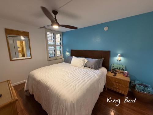 a bedroom with a king bed and a blue wall at 7-204 - Kama'ole Sands in Wailea