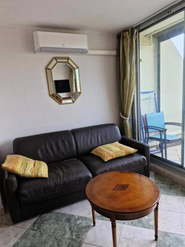 un salon avec un canapé en cuir noir et une table dans l'établissement Résidence Héliopolis Bâtiment L - HELIOPOLIS L - APPARTEMENT T2 - 4 pers. MAE-3074, au Cap d'Agde