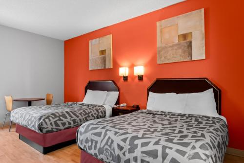 two beds in a room with orange walls at Scottish Inns & Suites - North Hershey in Harrisburg