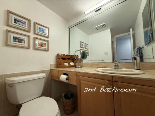 a bathroom with a toilet and a sink and a mirror at 7-204 - Kama'ole Sands in Wailea
