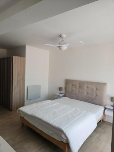 une chambre avec un grand lit et un ventilateur de plafond dans l'établissement Maison village de Bormes-les-Mimosas, à Bormes-les-Mimosas