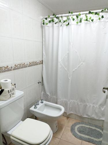 Baño blanco con aseo y cortina de ducha en Departamento Momó, en San Miguel de Tucumán