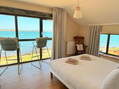 a bedroom with a bed with a view of the ocean at Le Chantier d 'Ernest- Loft T4 les pieds dans l' eau in Carantec