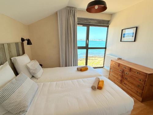 two beds in a bedroom with a view of the ocean at Le Chantier d 'Ernest- Loft T4 les pieds dans l' eau in Carantec