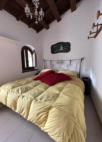 a bedroom with a large bed with yellow sheets and red pillows at At Nonna Maria's house in Casenove