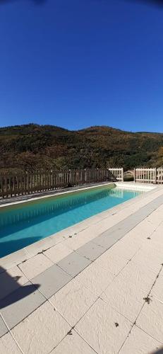 une piscine d'eau bleue et une clôture dans l'établissement la ferme de theolier, à Pailharès