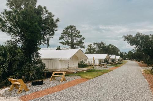 a row of white tents on a gravel road at Timberline Glamping Orange Beach in Gulf Shores