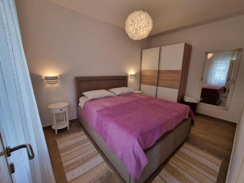 a bedroom with a large bed with a purple blanket at Apartments Kadenca in Omiš