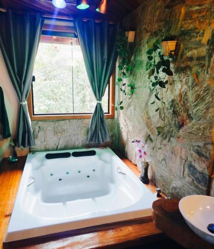 a large bath tub in a room with a window at Chalé Bosque das Pedras in Núcleo Mauá