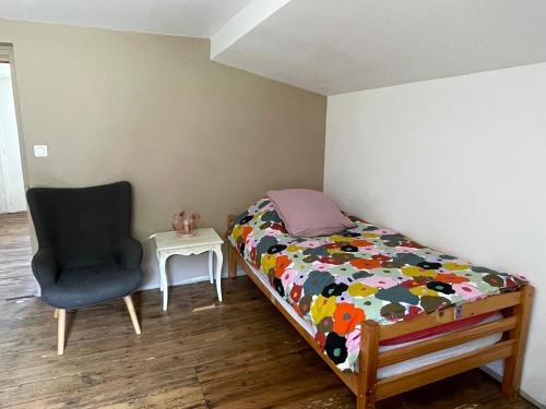 une petite chambre avec un lit et une chaise dans l'établissement La petite maison, à Sainte-Marie-de-Chignac