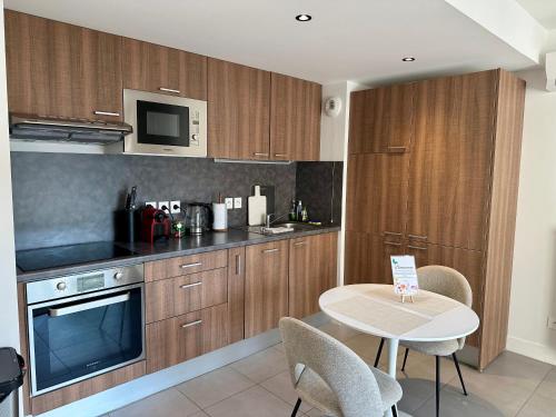 une cuisine avec des armoires en bois et une table avec des chaises dans l'établissement Appartement, cosy le Bouscat, à Le Bouscat