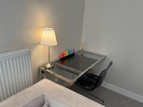 un bureau en verre avec une lampe et des livres dessus dans l'établissement Appartement, cosy le Bouscat, à Le Bouscat