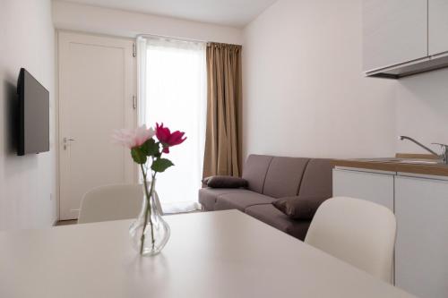 a living room with a vase of flowers on a table at Riviera Venice Apartments in Mira