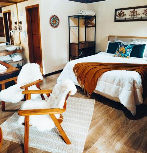 a bedroom with a large bed and a chair at Chalé Bosque das Pedras in Núcleo Mauá