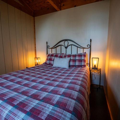 a bedroom with a bed with a plaid blanket and two lamps at Aspen - by The Chalets in Logan