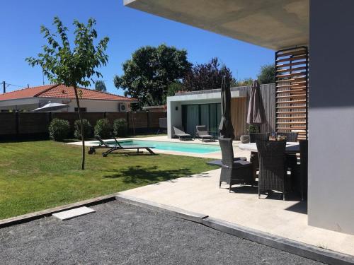 un patio avec une table et des chaises et une piscine dans l'établissement Villa paloma, à Gujan-Mestras