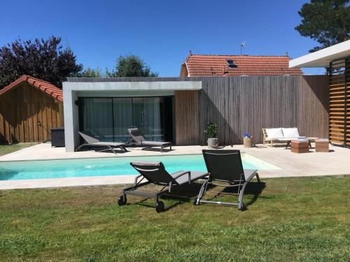 - deux chaises assises à côté de la piscine dans l'établissement Villa paloma, à Gujan-Mestras