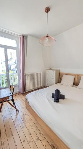 une chambre avec un grand lit blanc et une chaise dans l'établissement Villa Amica, Terrasse et jardin, à 50m de la plage, à Villers-sur-Mer