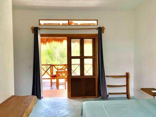 a room with a bed and a window with a door at The Jungle House, Sacbé in Playa del Carmen
