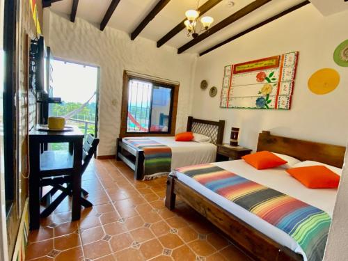 a bedroom with two beds and a desk and a window at Mamatina Hotel in Santa Rosa de Cabal