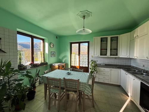 a green kitchen with a table and chairs in it at Rubattiera casa vacanze in Roccasparvera