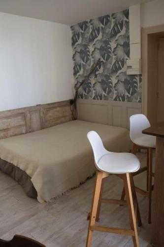 Cette chambre comprend un lit avec 2 chaises blanches. dans l'établissement agréables studios avec terrasse sur jardin, à Caussade