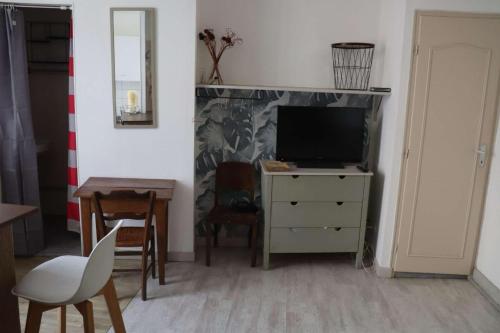 a living room with a television and a dining room table at agréables studios avec terrasse sur jardin in Caussade
