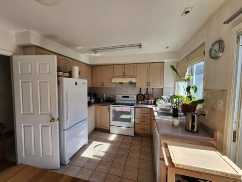 a kitchen with a white refrigerator and wooden cabinets at Scarborough Townhouse in Toronto