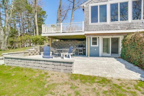 a house with a patio and a deck with two chairs at Patio and Pond View Serene Cape Cod Escape in Mashpee