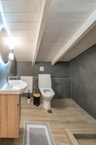 a bathroom with a white toilet and a sink at Solmare Loft Suite in Nikiana