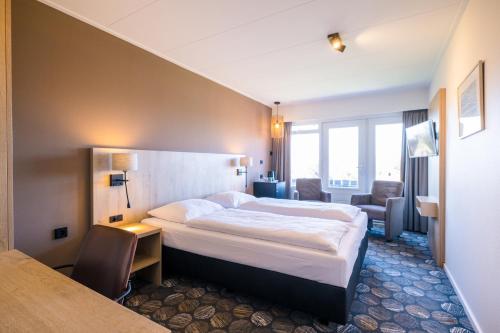 a hotel room with a large bed and a desk at Hotel Hofker in Nes