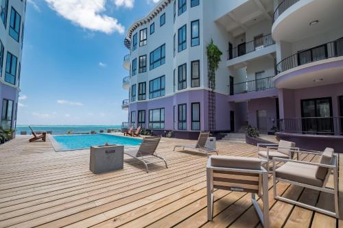 a large building with a pool and chairs and the ocean at Diamante Beachfront Suites in San Pedro