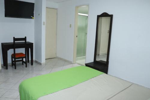 a bedroom with a bed and a desk and a mirror at Hotel Inambu Villavicencio in Villavicencio