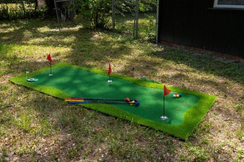 a miniature golf course with clubs and balls on it at 4BD Eclectic Home w/ BBQ & Mini Golf | Near UF in Paradise
