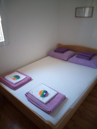 a bed with purple blankets and purple towels on it at Apartments M1 Pine tree in Sutomore
