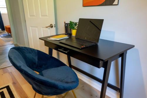a desk with a laptop computer on a blue chair at 4BD Eclectic Home w/ BBQ & Mini Golf | Near UF in Paradise