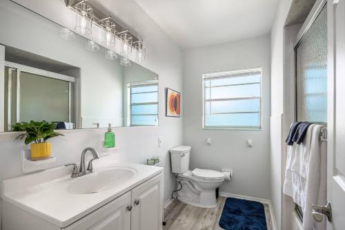 a white bathroom with a sink and a toilet at 4BD Eclectic Home w/ BBQ & Mini Golf | Near UF in Paradise