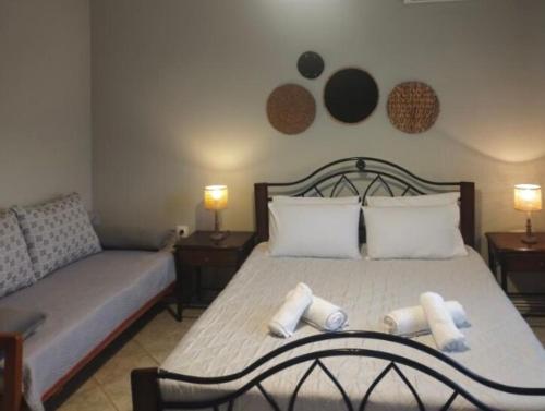 a bedroom with a bed with two pillows and a couch at Cleopatra's Cozy Cottage in Keramoti