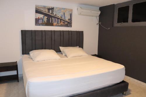 a bedroom with a large bed with white sheets at Hotel Inambu Villavicencio in Villavicencio